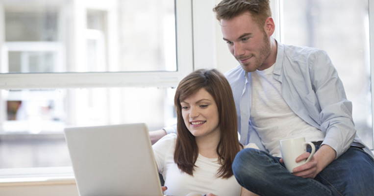 Couple sitting on couch browsing the interest on laptop