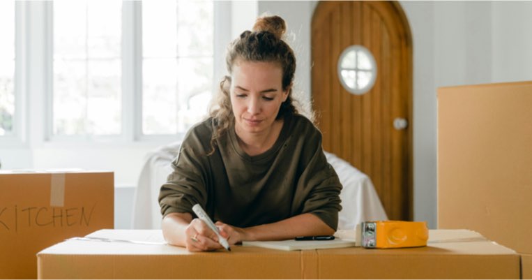 Lady writing notes on home-moving cardboard box