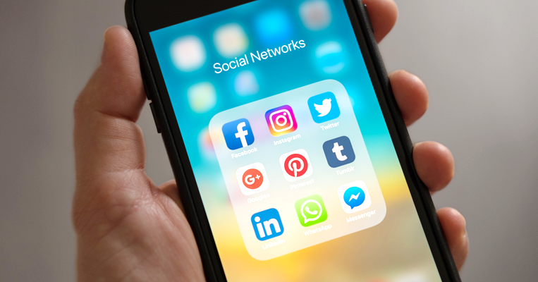 Hand holding smartphone with social network apps